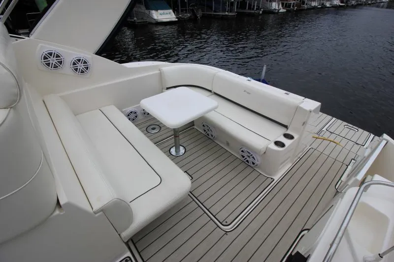 Slide: The Image of 2006 Cruisers Yachts 320 Express deck with white seating and table by the water. - 7