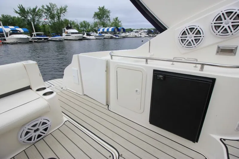 Slide: The Image of 2006 Cruisers Yachts 320 Express deck with seating, speakers, and marina view. - 8