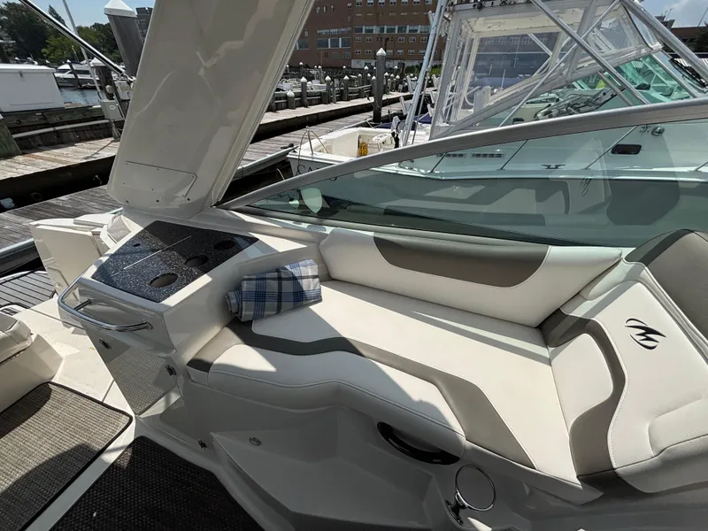 Slide: The Image of 2013 Monterey 280 SCR boat interior with cushioned seating and dockside view. - 19