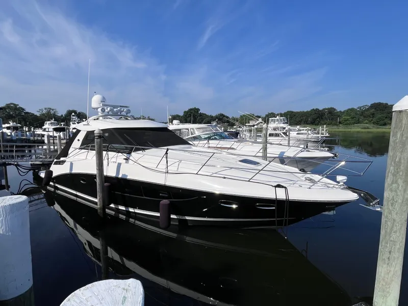The Image of 2013 Sea Ray 450 Sundancer yacht docked at marina under clear blue sky. - 0