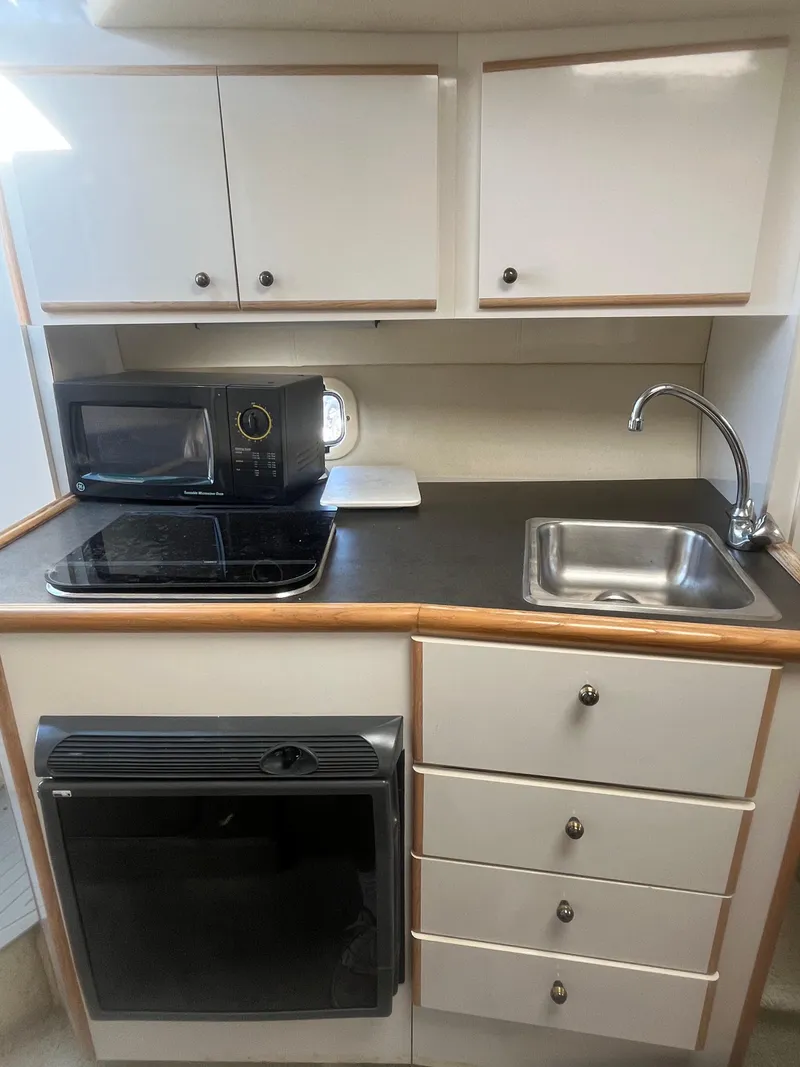 Slide: The Image of Compact kitchen in a 1996 Maxum 2700 SCR boat with sink, microwave, and stove. - 13