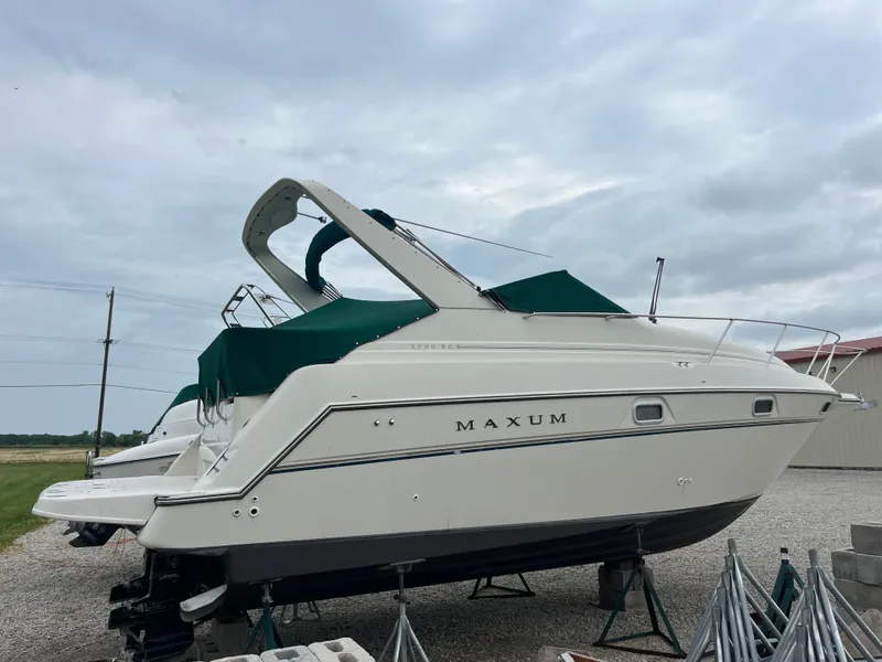 Slide: The Image of 1996 Maxum 2700 SCR boat with green canopy, displayed on stands outdoors. - 15