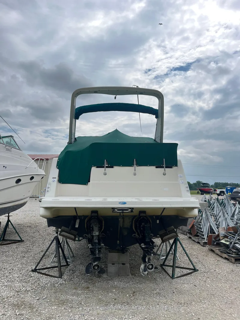 Slide: The Image of 1996 Maxum 2700 SCR boat on stands, covered with green tarp, cloudy sky background. - 3