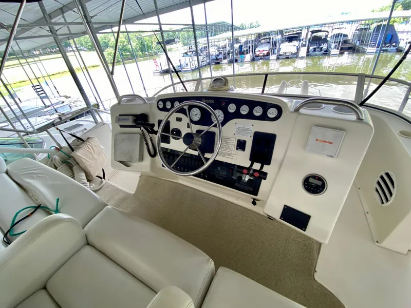 Slide: The Image of 1997 Silverton 372 Motor Yacht helm with steering wheel and control panel in marina setting. - 15