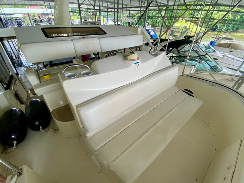 Slide: The Image of 1997 Silverton 372 Motor Yacht interior with seating and cup holders in a marina setting. - 19