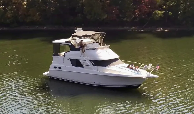 Slide: The Image of 1997 Silverton 372 Motor Yacht cruising on a calm lake with lush green surroundings. - 3