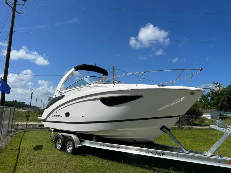 Slide: The Image of 2024 Regal 26 XO boat on trailer under clear blue sky. - 1
