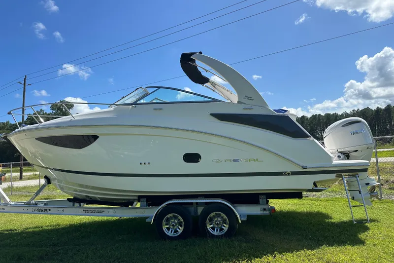 Slide: The Image of 2024 Regal 26 XO boat on trailer, parked on grass under blue sky. - 11