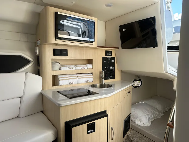 Slide: The Image of 2024 Regal 26 XO cabin interior with kitchenette, microwave, TV, and sleeping area. - 21