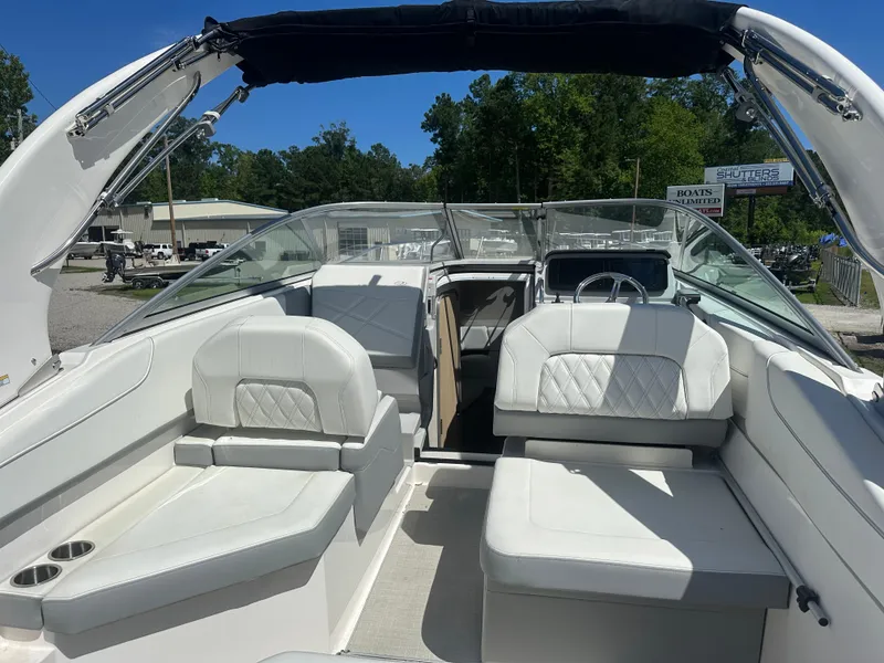 Slide: The Image of 2024 Regal 26 XO boat interior with white seating and canopy, parked outdoors. - 8