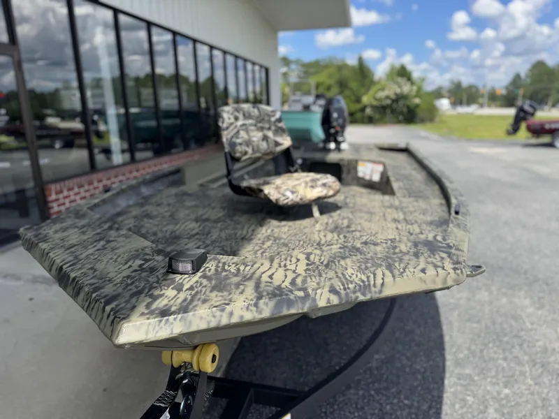 Slide: The Image of 2026 Tracker Grizzly 1654 T Sportsman boat with camouflage design, parked outdoors. - 11