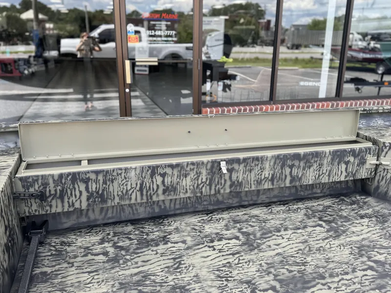 Slide: The Image of 2026 Tracker Grizzly 1654 T Sportsman boat with open storage compartment, camo pattern design. - 12