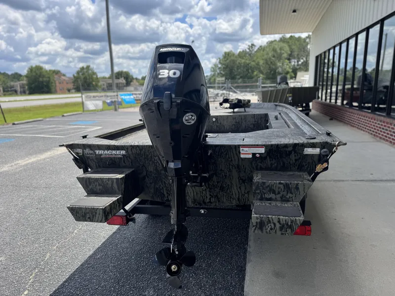 Slide: The Image of 2026 Tracker Grizzly 1654 T Sportsman boat with Mercury 30 engine, parked outdoors. - 5