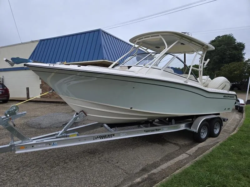 Slide: The Image of 2026 Grady-White Freedom 255 boat on trailer, parked outdoors near a blue-roofed building. - 3