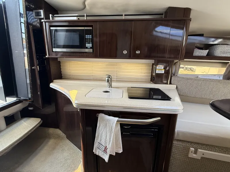 Slide: The Image of 2017 Sea Ray Sundancer 280 interior kitchen with microwave, sink, and stove. - 16