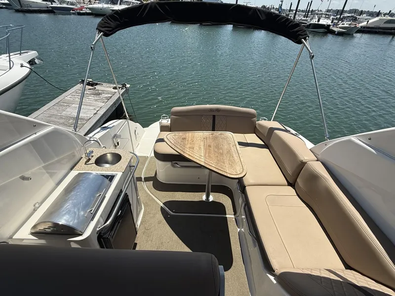 Slide: The Image of 2017 Sea Ray Sundancer 280 boat interior with seating, table, and kitchenette by the water. - 8