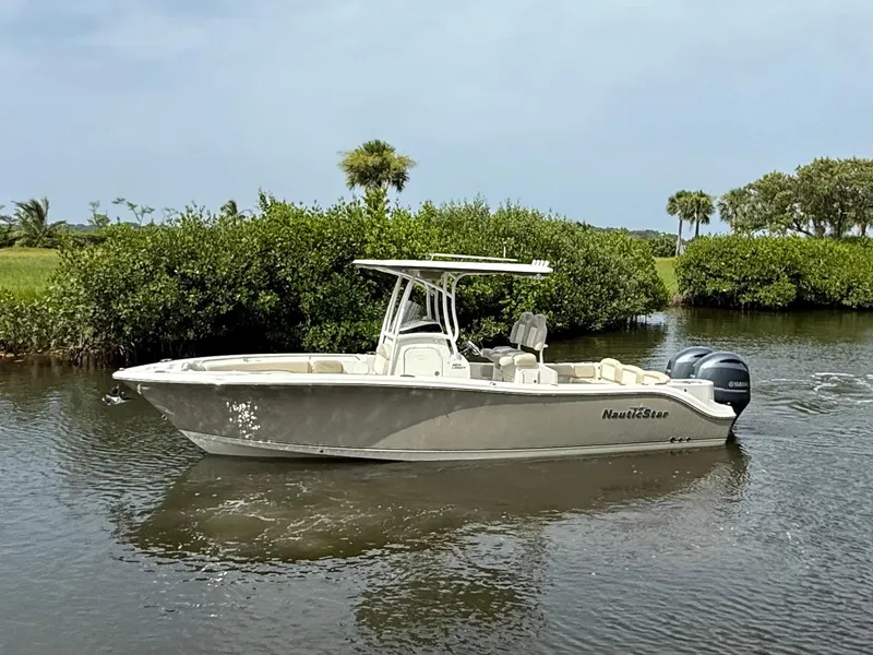 Slide: The Image of 2017 NauticStar 2602 Legacy boat on calm water, surrounded by lush greenery. - 0