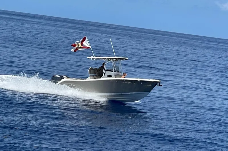 Slide: The Image of 2017 NauticStar 2602 Legacy boat cruising on open ocean with flag. - 2