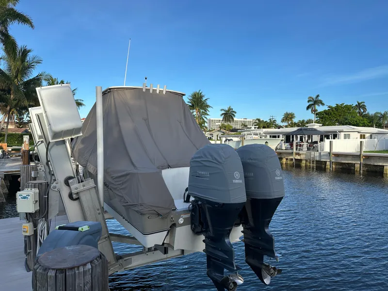 Slide: The Image of 2017 NauticStar 2602 Legacy boat docked with covered engines, surrounded by palm trees. - 4