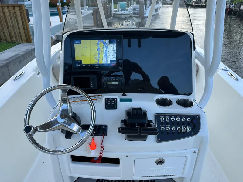 Slide: The Image of 2017 NauticStar 2602 Legacy boat dashboard with steering wheel and navigation system. - 8
