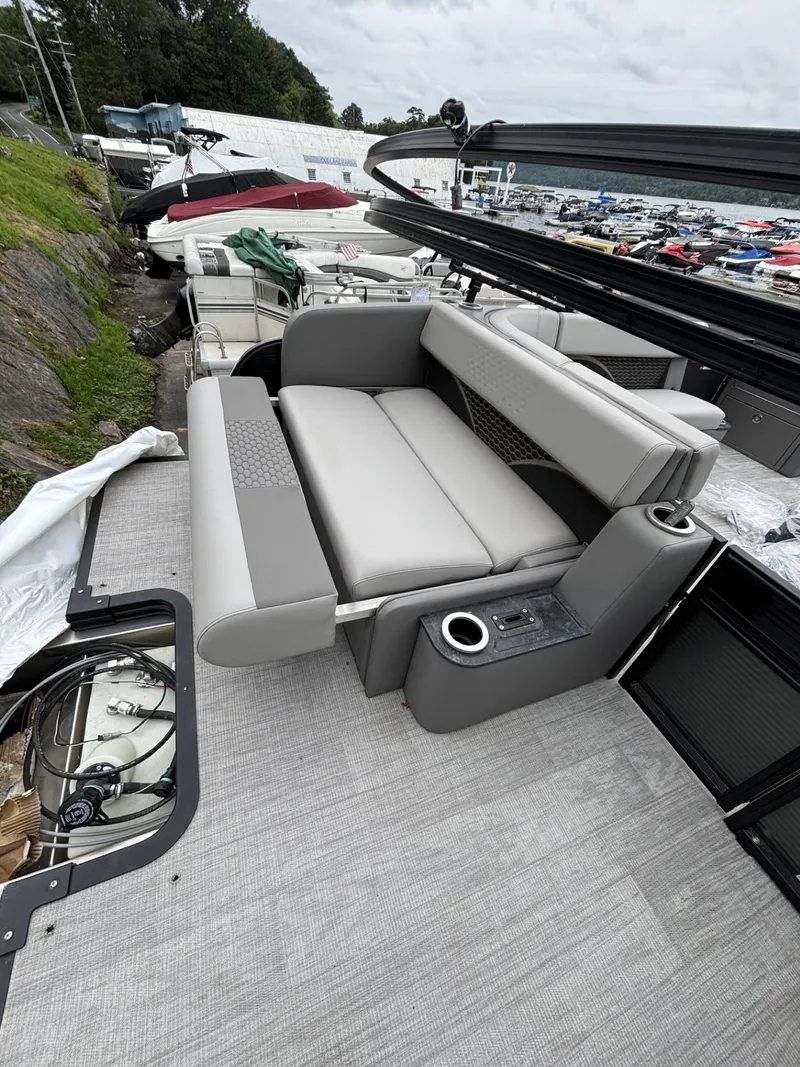 Slide: The Image of 2023 Qwest Lanai 822 pontoon boat with gray seating and cup holders, docked outdoors. - 5
