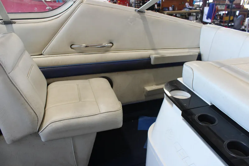 Slide: The Image of Interior of a 1994 Celebrity 230 BR boat with white seating and cup holders. - 18