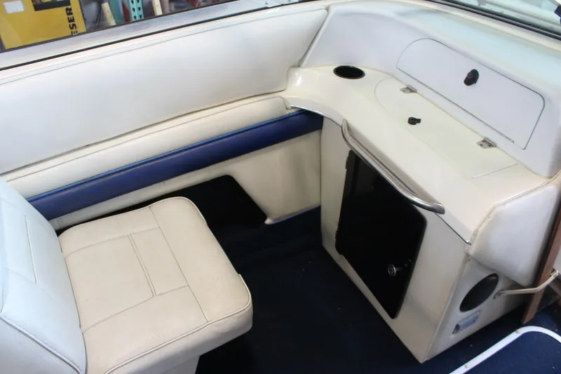 Slide: The Image of Interior of a 1994 Celebrity 230 BR boat with white seating and storage compartments. - 23