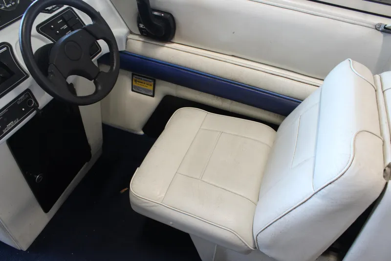 Slide: The Image of Interior of a 1994 Celebrity 230 BR boat with white seating and steering wheel. - 24