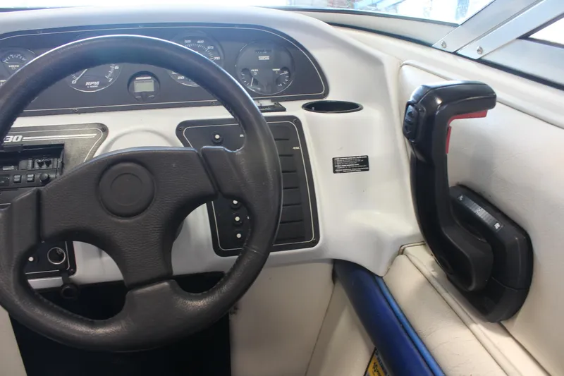 Slide: The Image of Steering wheel and controls of a 1994 Celebrity 230 BR boat dashboard. - 27