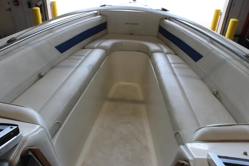 Slide: The Image of Interior of a 1994 Celebrity 230 BR boat with white seating and blue accents. - 29
