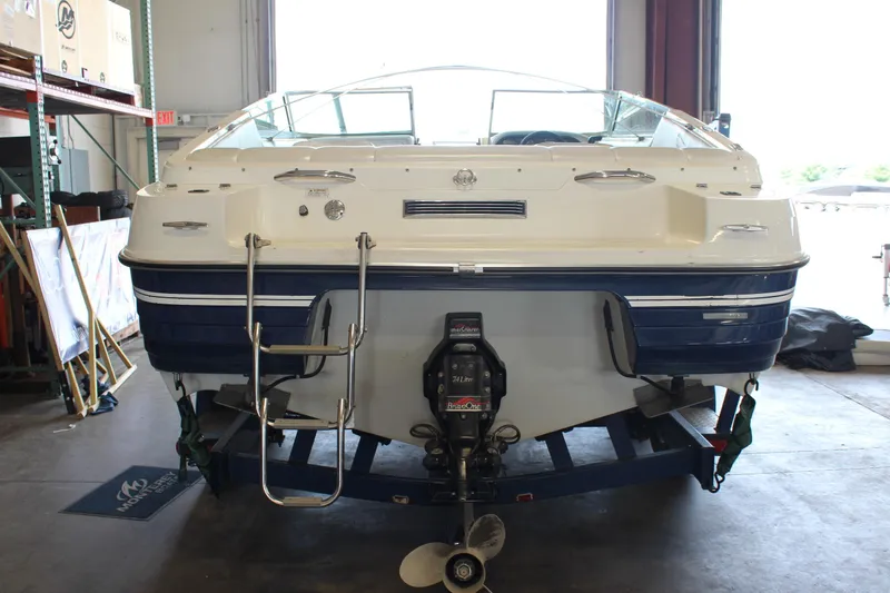 Slide: The Image of 1994 Celebrity 230 BR boat in a garage, rear view with ladder and motor visible. - 5