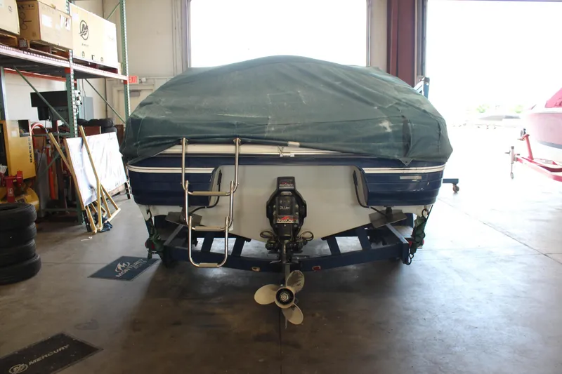 Slide: The Image of Covered 1994 Celebrity 230 BR boat in a garage, rear view with visible propeller. - 7