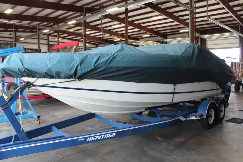 Slide: The Image of Covered 1994 Celebrity 230 BR boat on a blue trailer in a warehouse. - 9