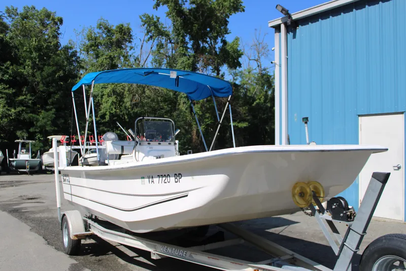 Slide: The Image of 2010 Carolina Skiff 2180 DLX boat on trailer with blue canopy, parked outdoors. - 1