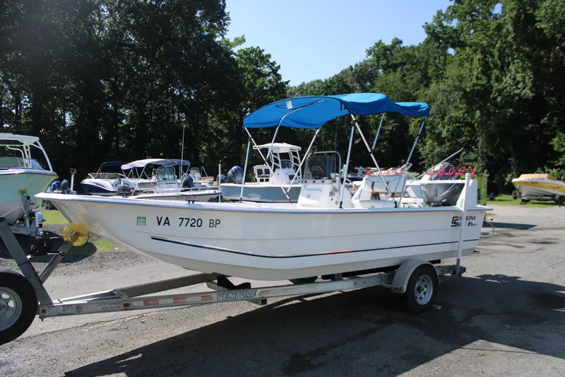 Slide: The Image of 2010 Carolina Skiff 2180 DLX boat on trailer with blue canopy, parked outdoors. - 2