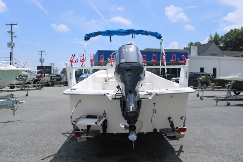Slide: The Image of 2010 Carolina Skiff 2180 DLX boat with outboard motor, parked outdoors under blue sky. - 8