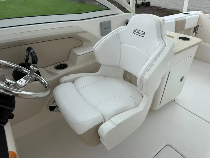 Slide: The Image of 2018 Robalo R247 Dual Console boat interior with white captain's chair and steering wheel. - 13