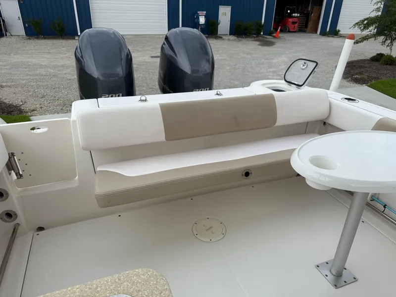 Slide: The Image of 2018 Robalo R247 Dual Console boat interior with seating and table, featuring twin engines. - 16