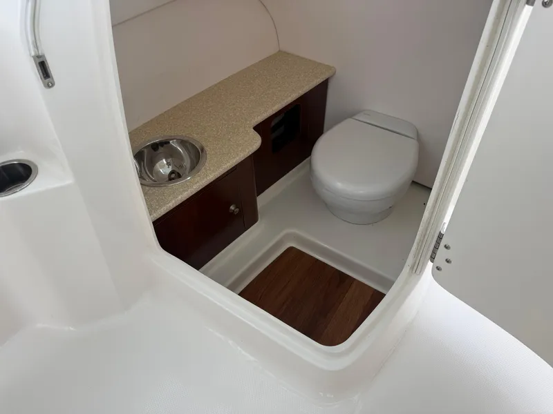 Slide: The Image of 2018 Robalo R247 Dual Console boat interior with toilet and sink. - 17