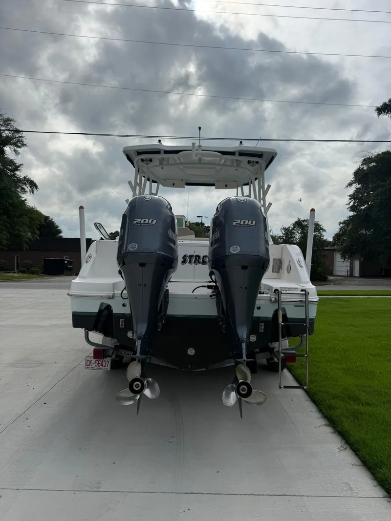 Slide: The Image of 2018 Robalo R247 Dual Console boat with twin 200 horsepower engines, parked on concrete. - 4