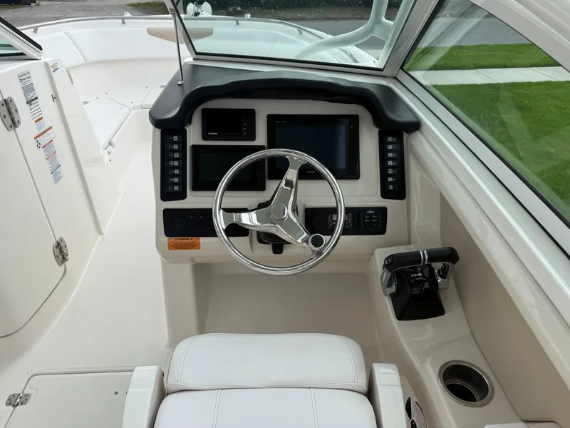 Slide: The Image of 2018 Robalo R247 Dual Console boat cockpit with steering wheel and control panel. - 8