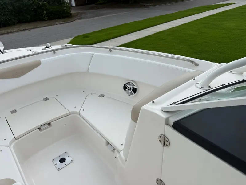 Slide: The Image of 2018 Robalo R247 Dual Console boat interior with seating and speaker, parked on grass. - 9