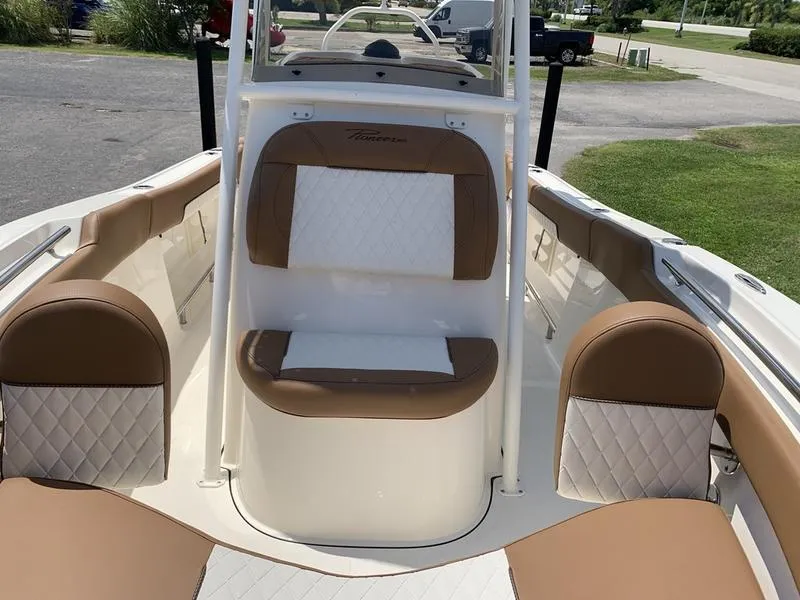 Slide: The Image of 2026 Pioneer ISLANDER 202 boat interior with tan and white seating, parked outdoors. - 26