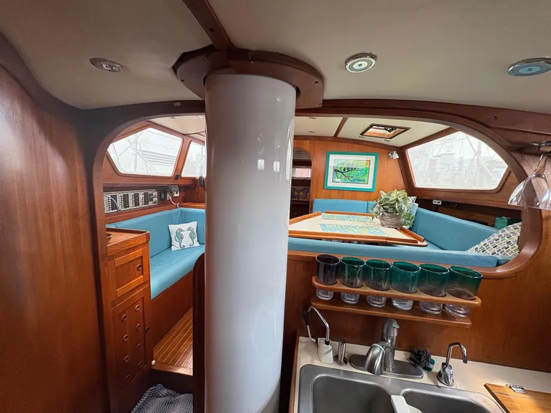 Slide: The Image of 1984 Freedom 39 Pilothouse interior with wood finish, blue seating, and kitchen area. - 24
