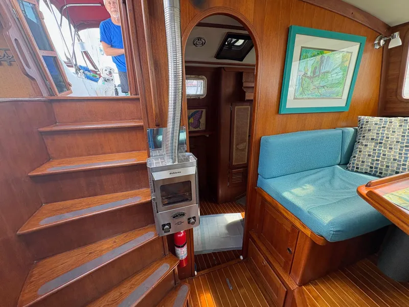 Slide: The Image of 1984 Freedom 39 Pilothouse interior with wood finish, blue seating, and a small stove. - 25