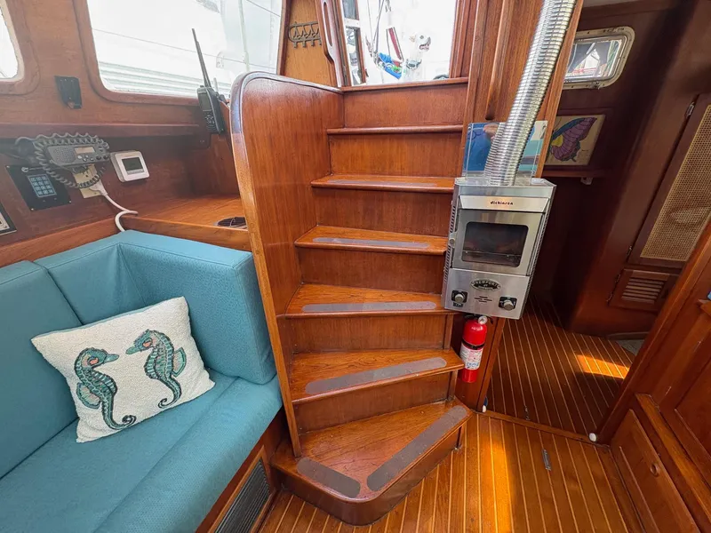 Slide: The Image of 1984 Freedom 39 Pilothouse interior with wooden stairs, stove, and seahorse pillow on blue seating. - 47