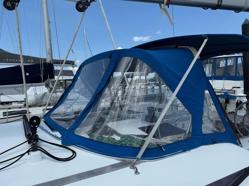 Slide: The Image of 2015 Jeanneau 409 sailboat with blue canopy and clear windows at marina. - 16