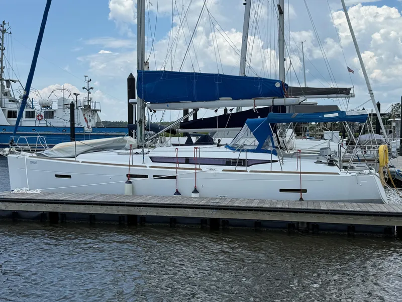 Slide: The Image of 2015 Jeanneau 409 sailboat docked at marina under cloudy sky. - 2
