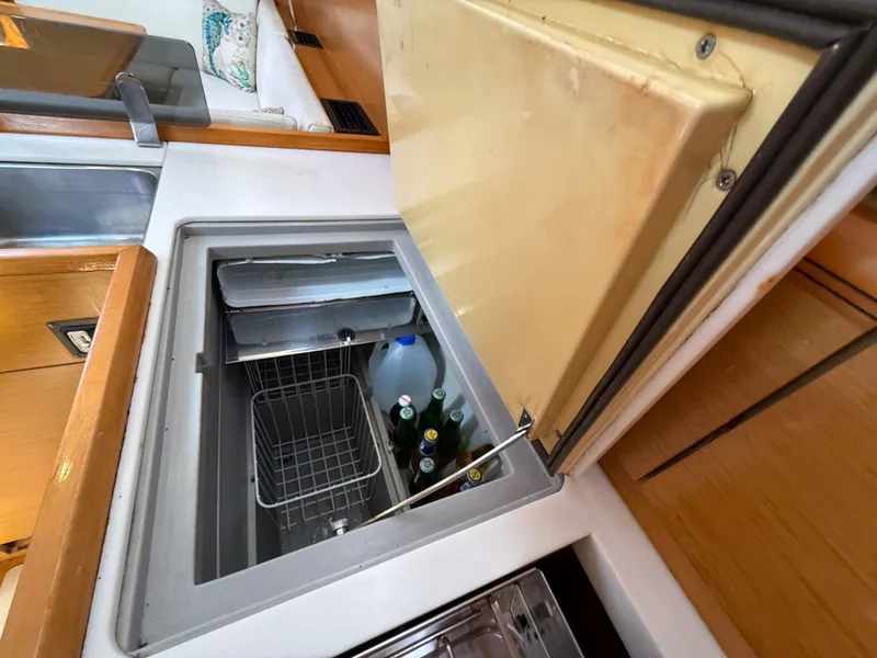 Slide: The Image of Jeanneau 409 yacht interior with open fridge, showcasing beverages and storage space. - 24