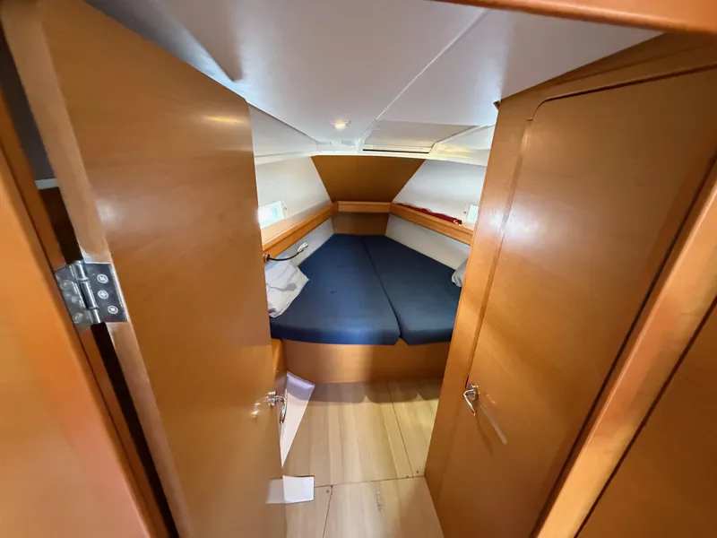 Slide: The Image of 2015 Jeanneau 409 cabin interior with wooden finish and blue bedding. - 27